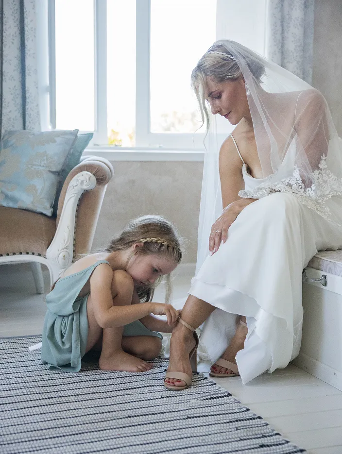 Girl tying bride's shoe on her wedding day. Wedding photography