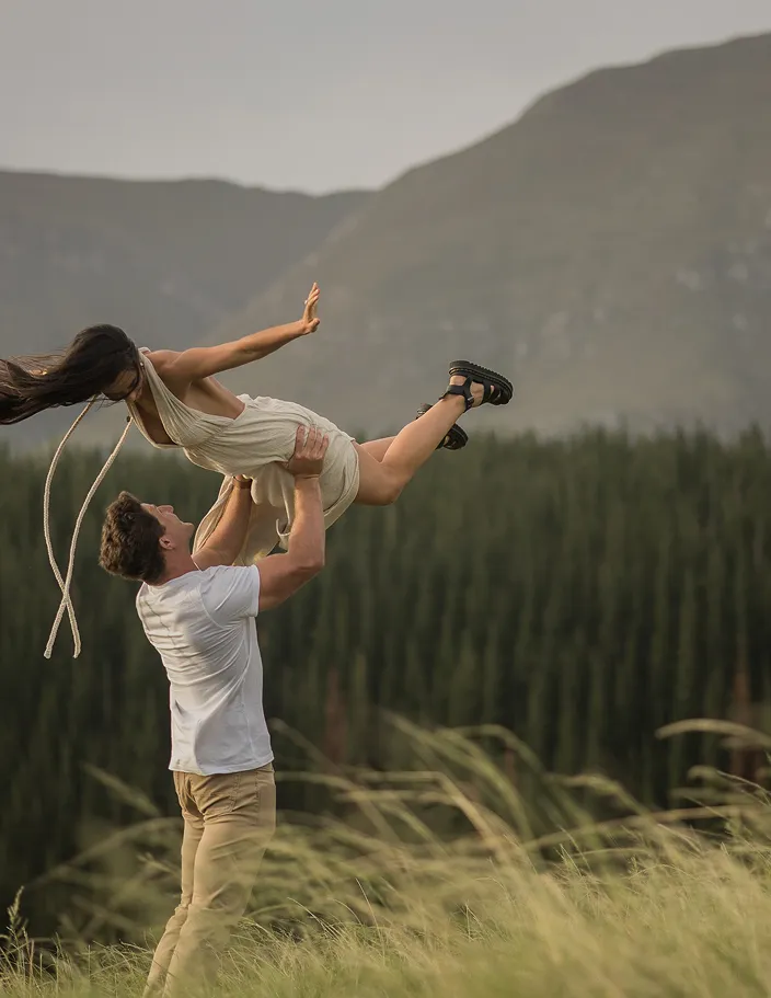 Couple outside while man holds women up in the air