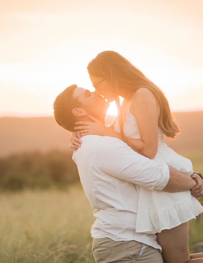 Couple kissing each other with sunset behind them