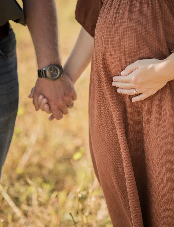 Couple holding hands showing maternity