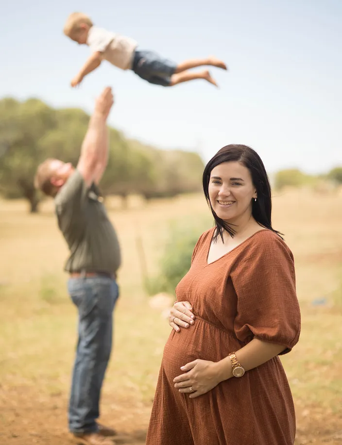 Family picture with dad playing with son and pregnant mom looking at camera