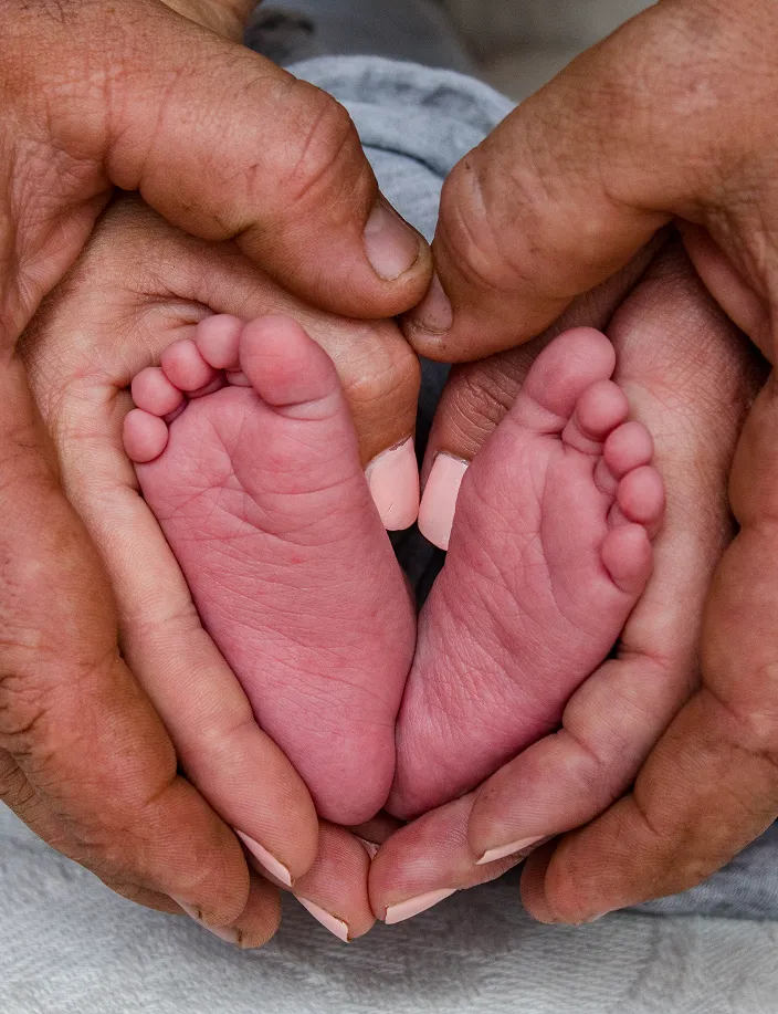 Newborn feet held in family hands
