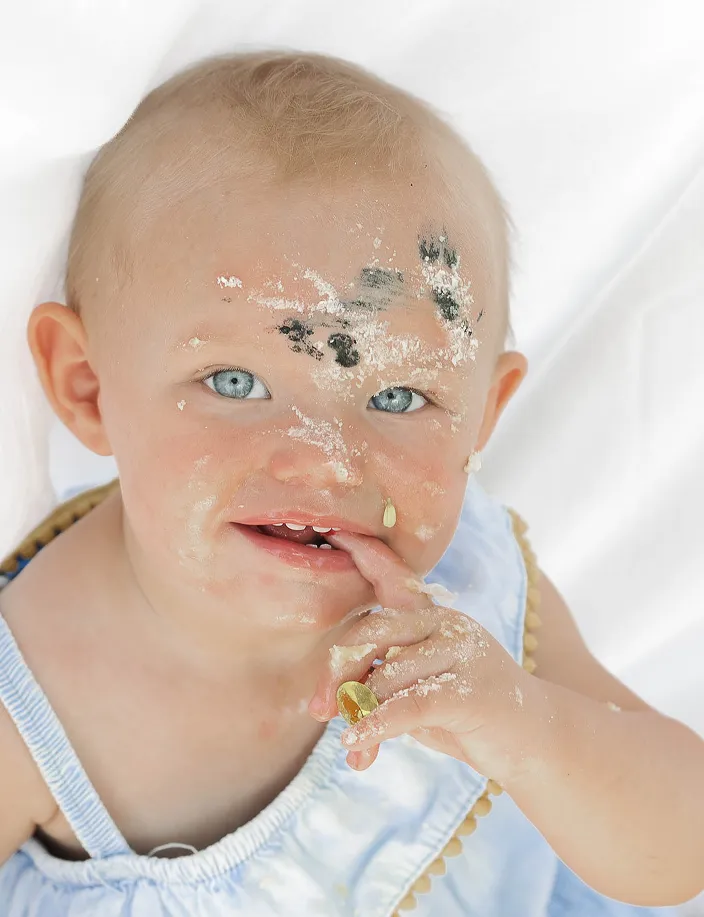 Newborn with cake all over their face