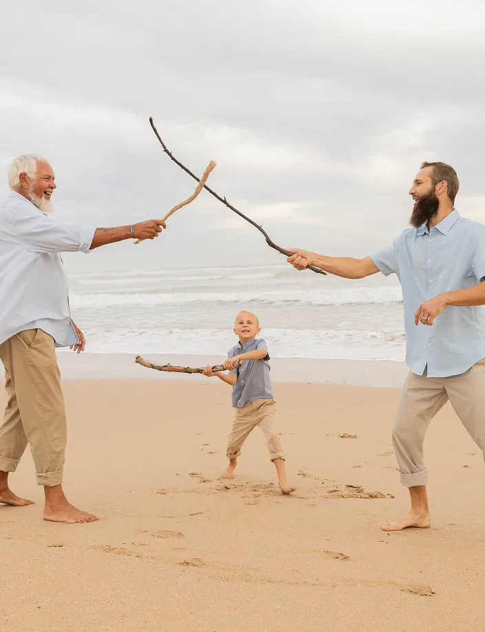 Three generations playfully bond with sticks on a peaceful beach.