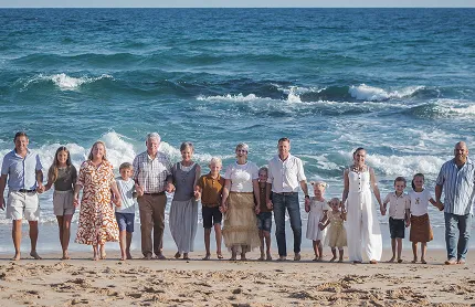 Multigenerational family united on beach, joyful amidst ocean waves