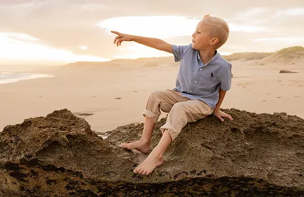 Portrait image of boy pointing to the distance.